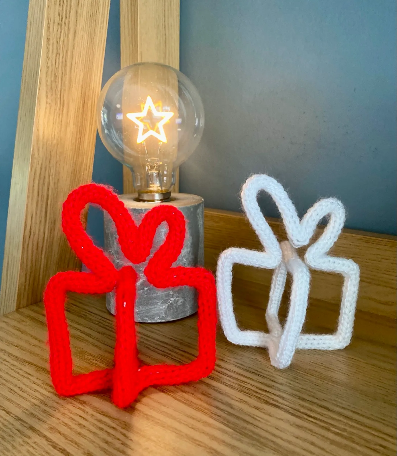 Knitted gift box: A knitted present with a bow on top, in red or white.