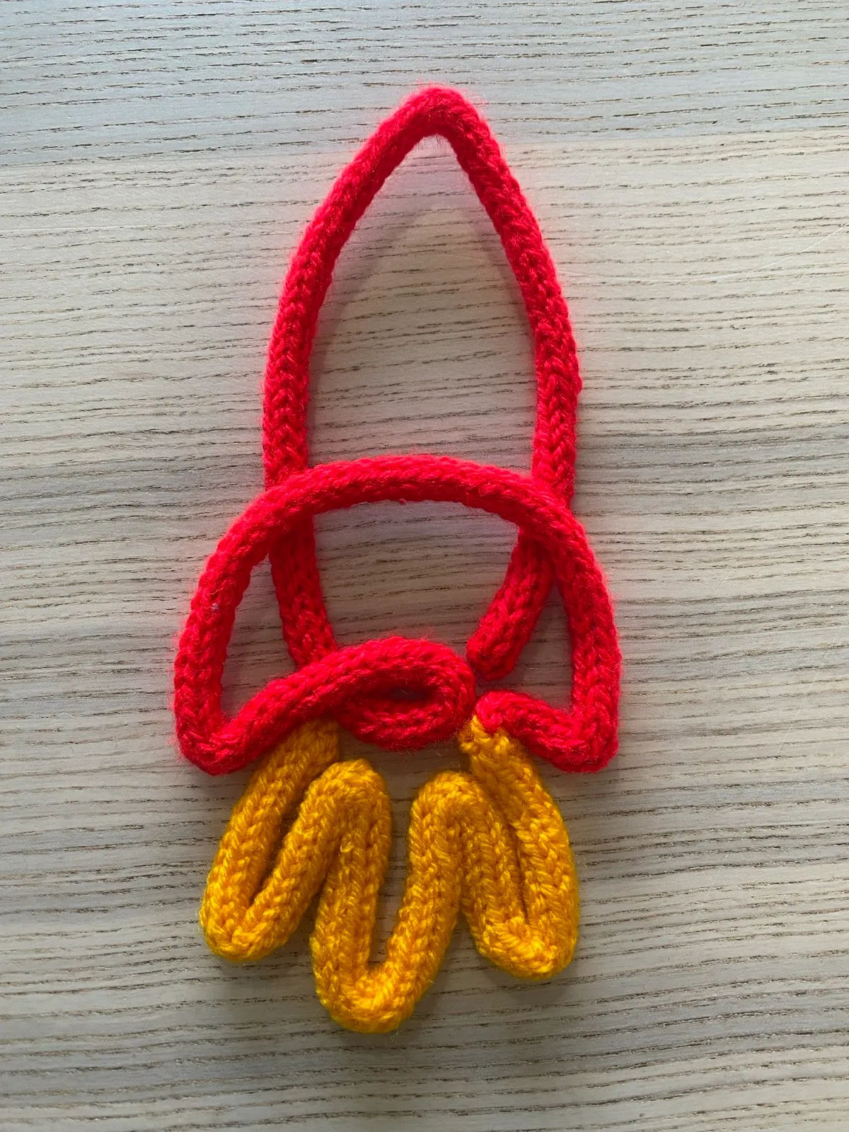 Rocket: A red knitted rocket with yellow flames, ready for blast off.