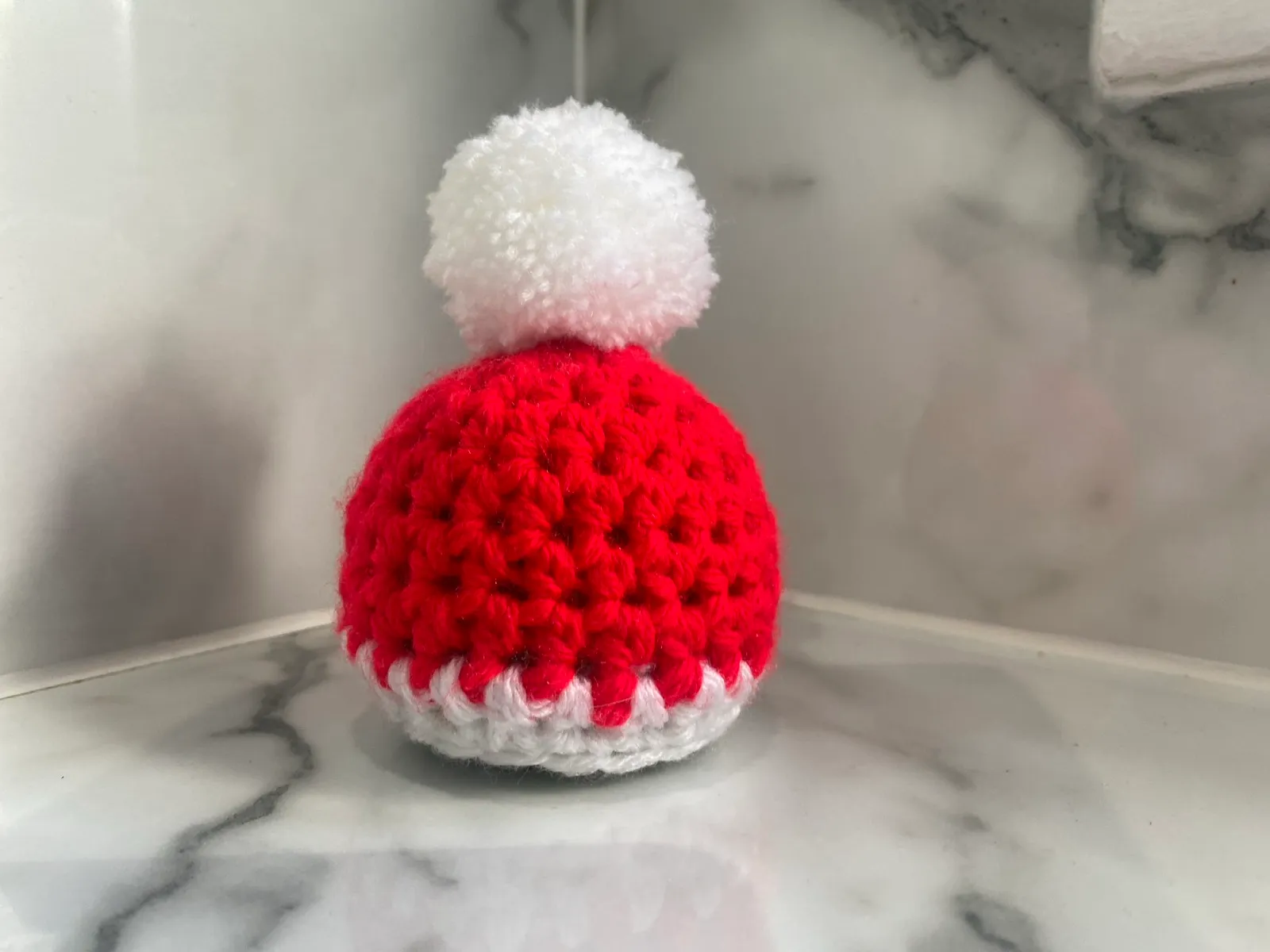 Santa/elf hat chocolate orange cosy: A crocheted Santa or elf hat with a pom-pom, sized for a chocolate orange.